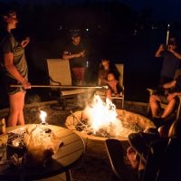 Family roasting marshmallows around a backyard firepit