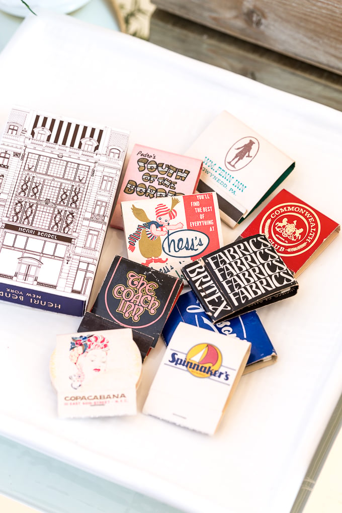 Use what you have decor. Matchbook collection gathered on plate then set on a stack of books on a coffee table.