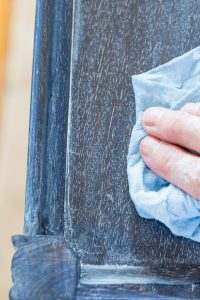 How to rub in clear wax on a dark blue color washed piece of furniture so the finish will have protection and a subtle sheen.