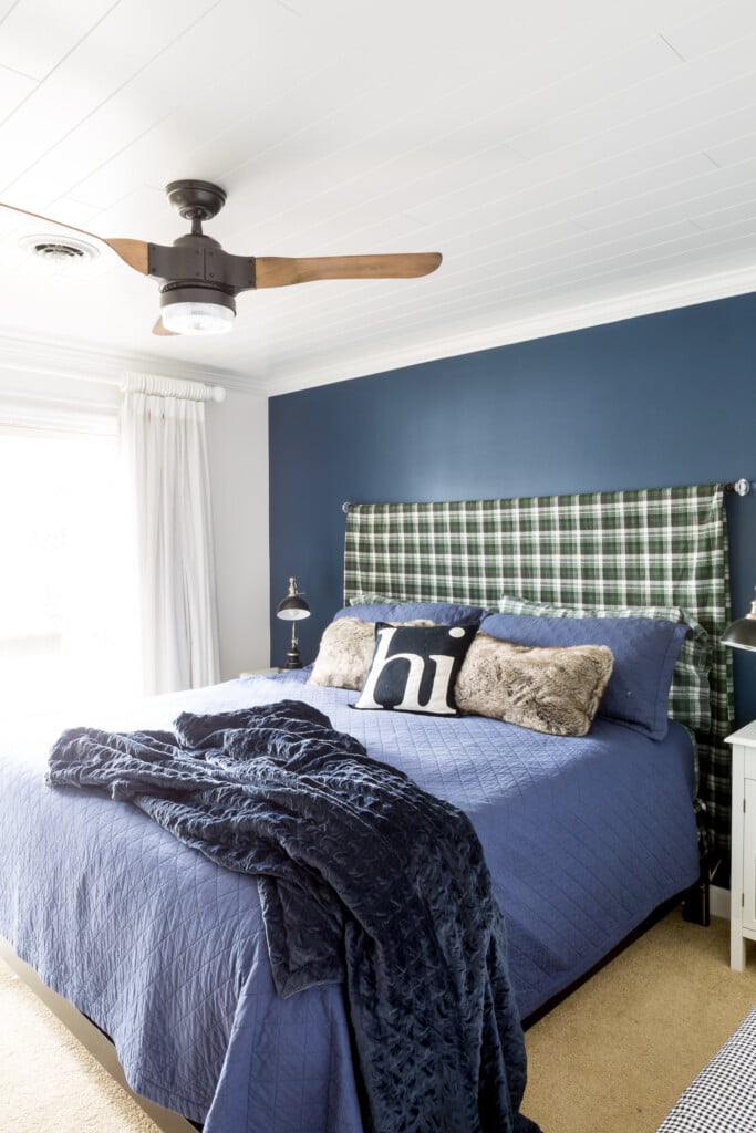 Blue accent wall with plaid sheet made into a king size headboard.