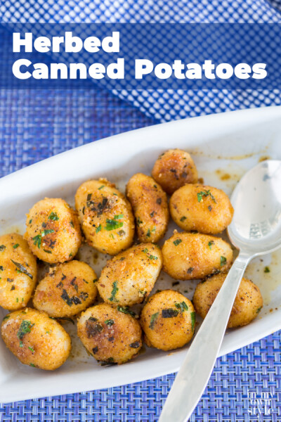 Herbed Encrusted Canned Potatoes in a white serving dishes being spooned out.