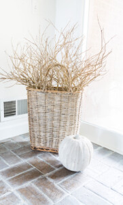 Tall handled basket with stone pumpkin in front of it.