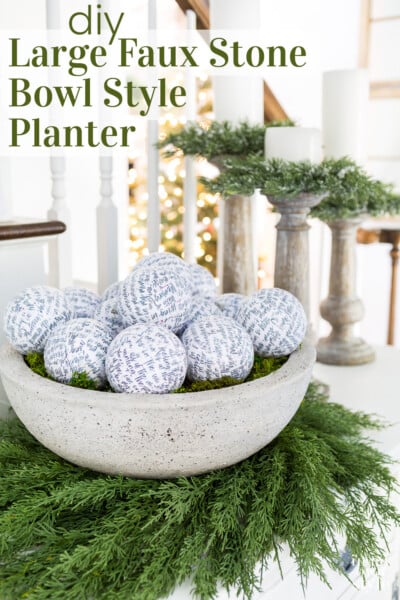 Large faux cement bowl on a wreath on a sideboard. Text overlay says DIY large faux stone bowl style planter.