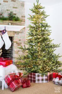 Living room with Christmas tree that has a plaid fabric wrapped frame tree collar around the stand.