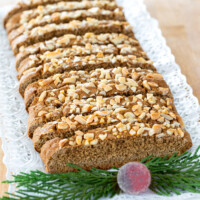 Vegan biscotti cut into slices on a plate with Christmas greenery on it.