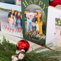 Completed Christmas card holder with greenery in front of it on a console table.