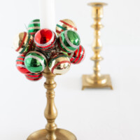 Brass candle holder with green red and gold mini Shiny Brite ball ornaments made into a taper candle collar.