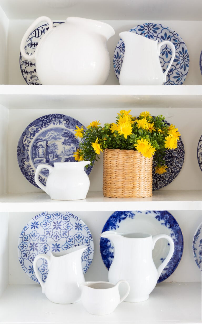 a collection of white ceramic pitchers displayed on open shelves in a kitchen.
