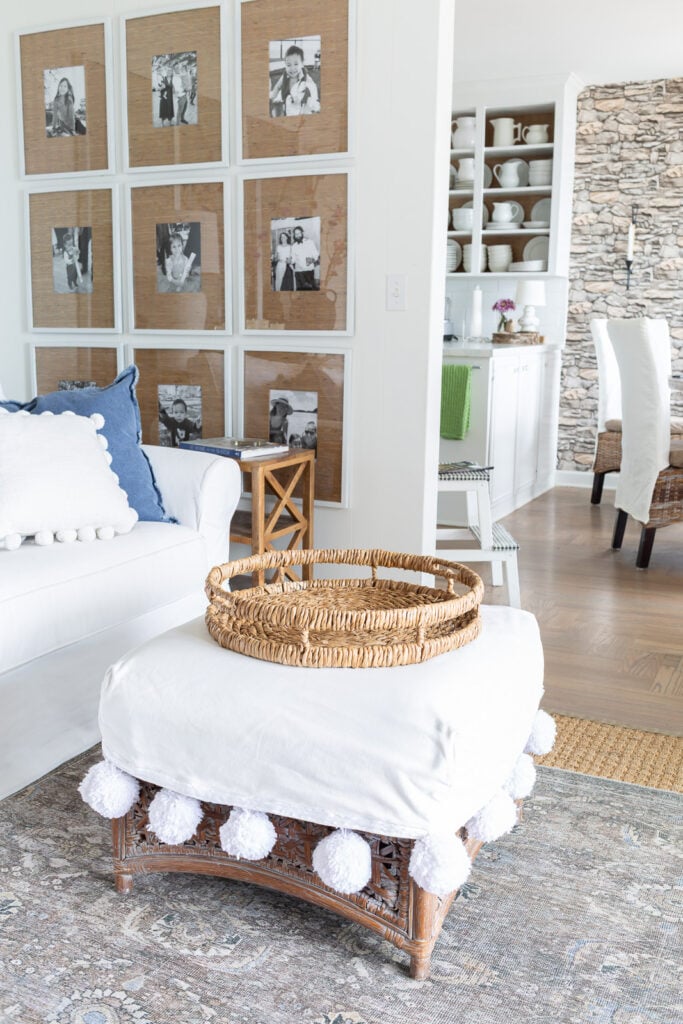 Round rattan tray on white slipcovered ottoman.