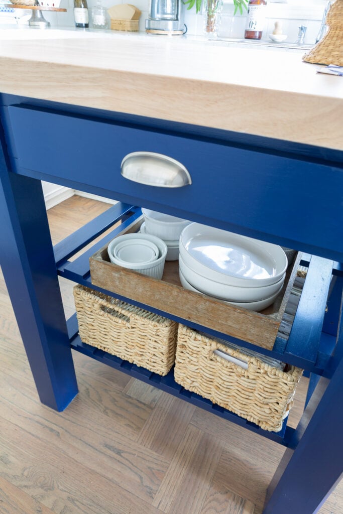 Close up of painted kitchen work table island with two shelves and a drawer for storage.