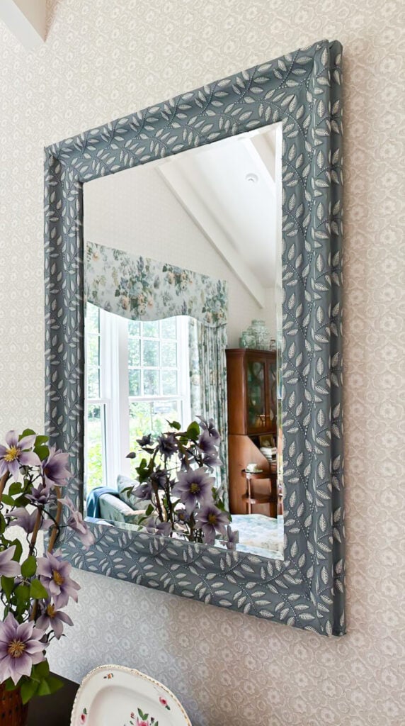 textured woven fabric covering the frame of a mirror in a bedroom