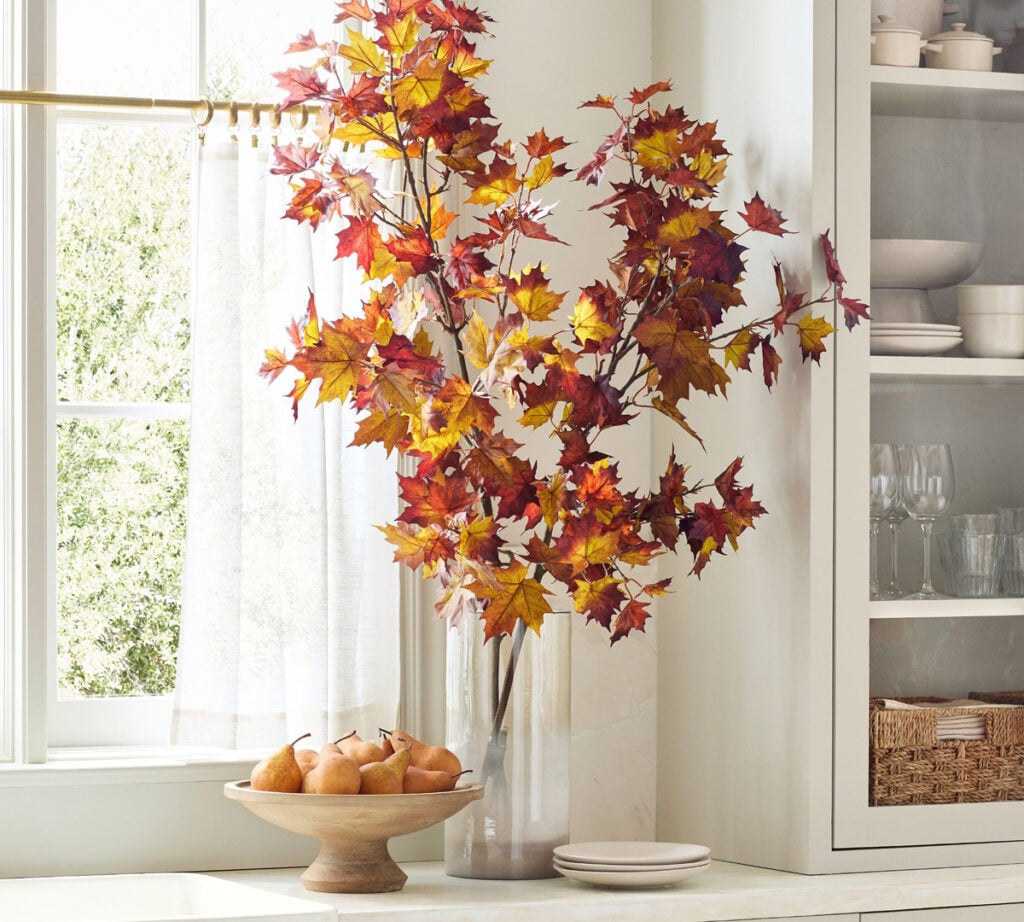faux branches in glass vase on kitchen counter
