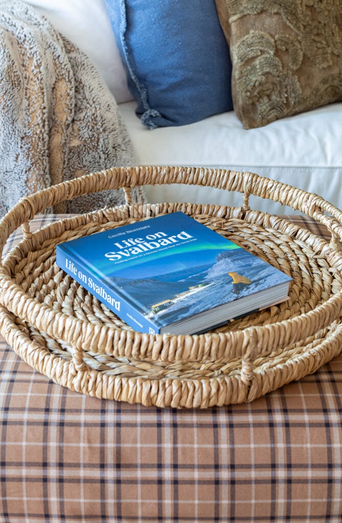 round woven tray with a blue coffee table book on with the title Life on Svalbard