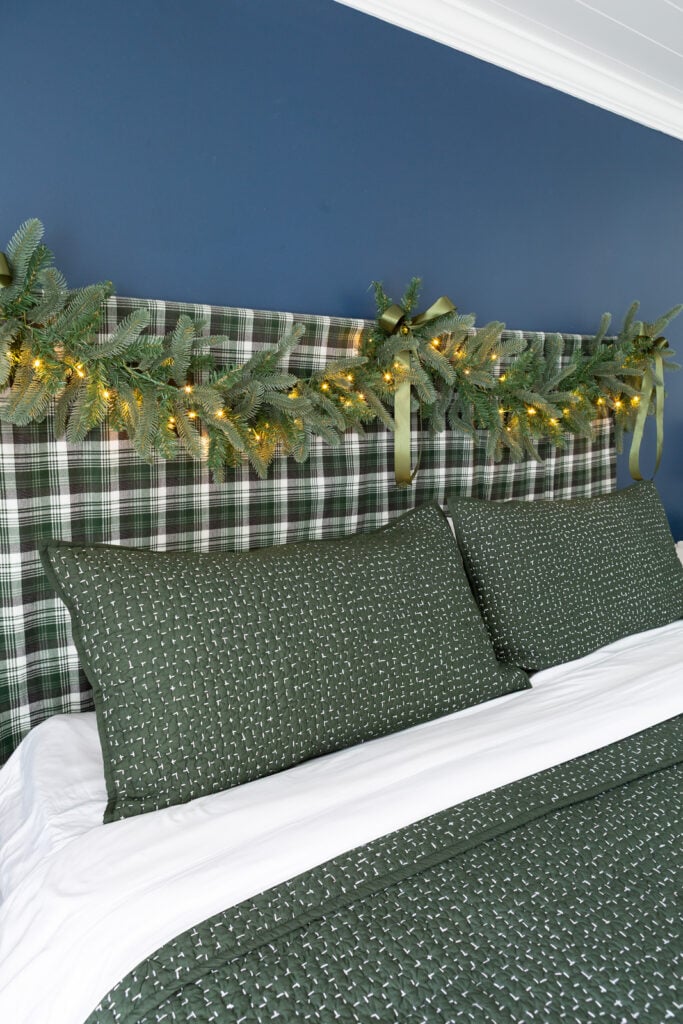 Bed headboard decorated for Christmas with a King of Christmas Noble Fir garland