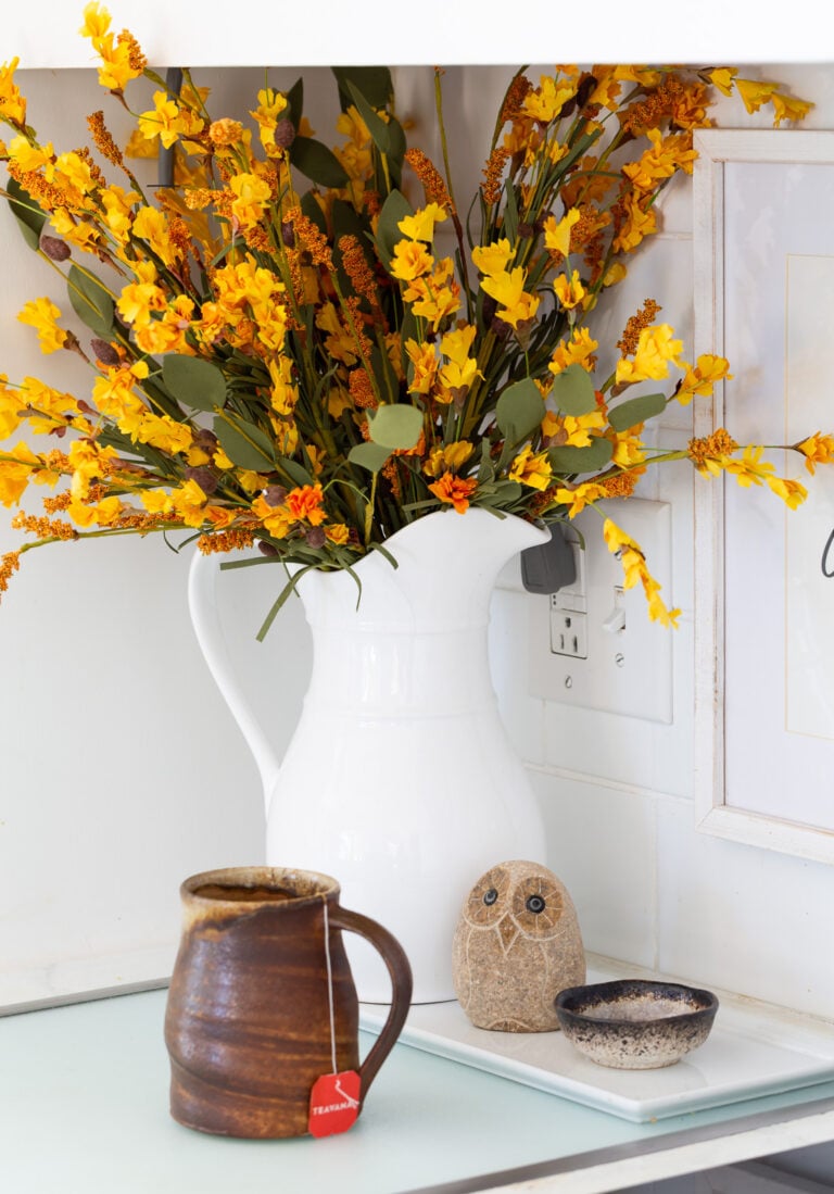 white ceramic pitcher on kitchen counter filled with fall foliage.