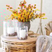 wicker table topped with fall decor - candles and fall colored faux florals.