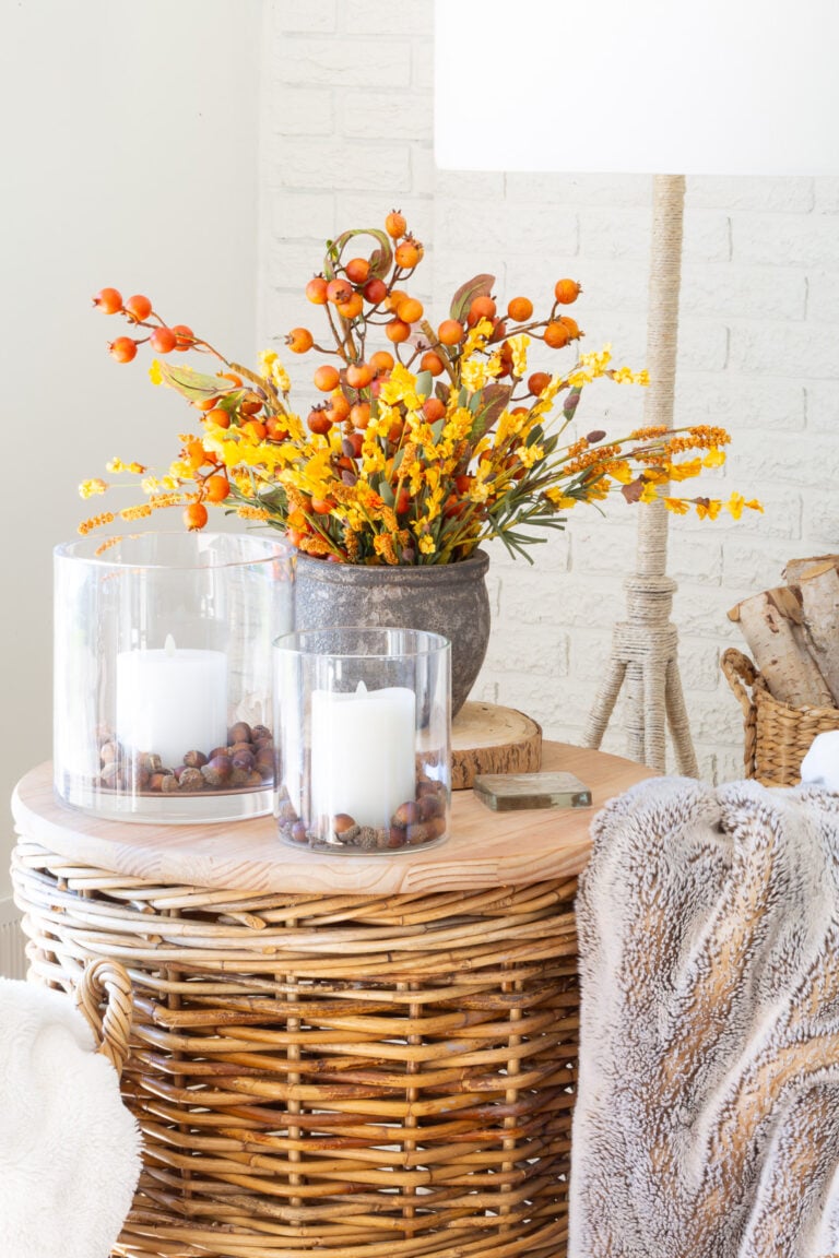 wicker table topped with fall decor - candles and fall colored faux florals.