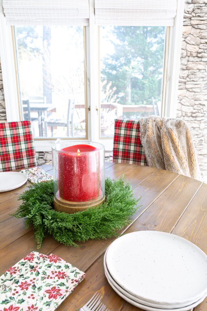 Looking at a round wood dining table with red and white Christmas plaid fabric covers on al the dining chairs.