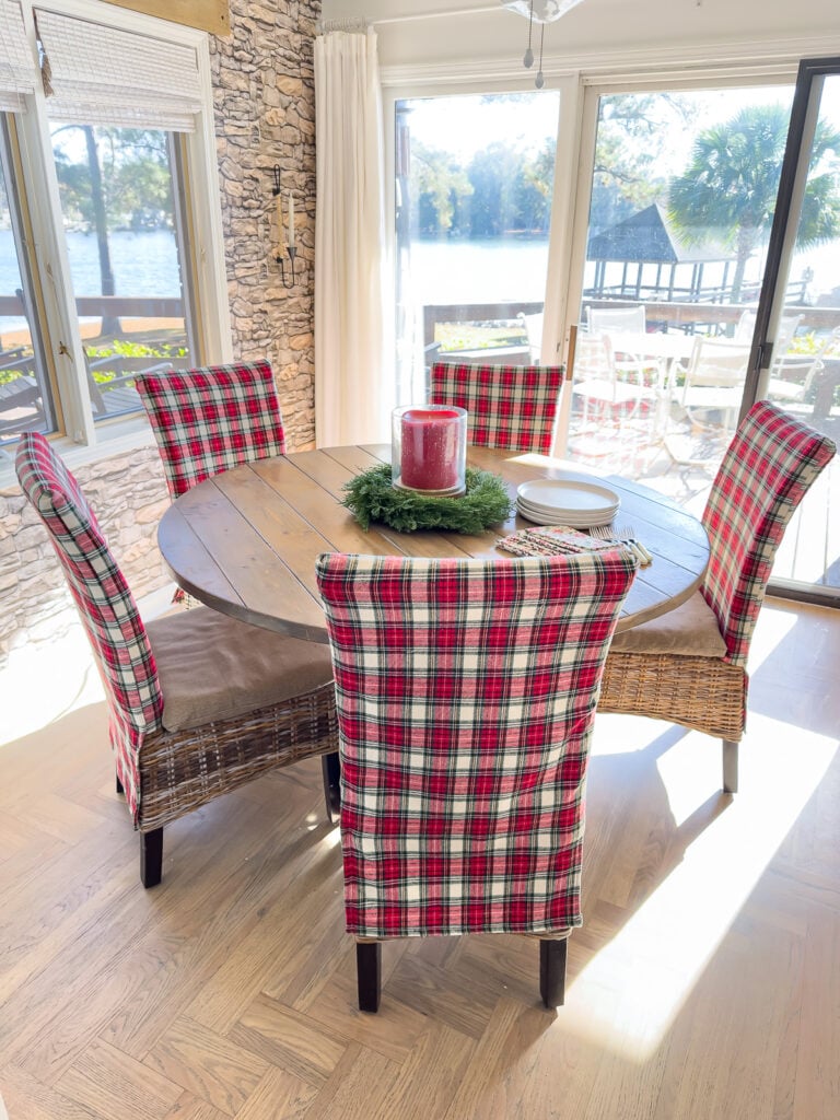 Round wood kitchen table with Christmas plaid fabric covered dining chairs around it.