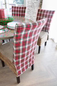 Looking at the back of one of the classic holiday plaid fabric covered dining chairs around a dining table.
