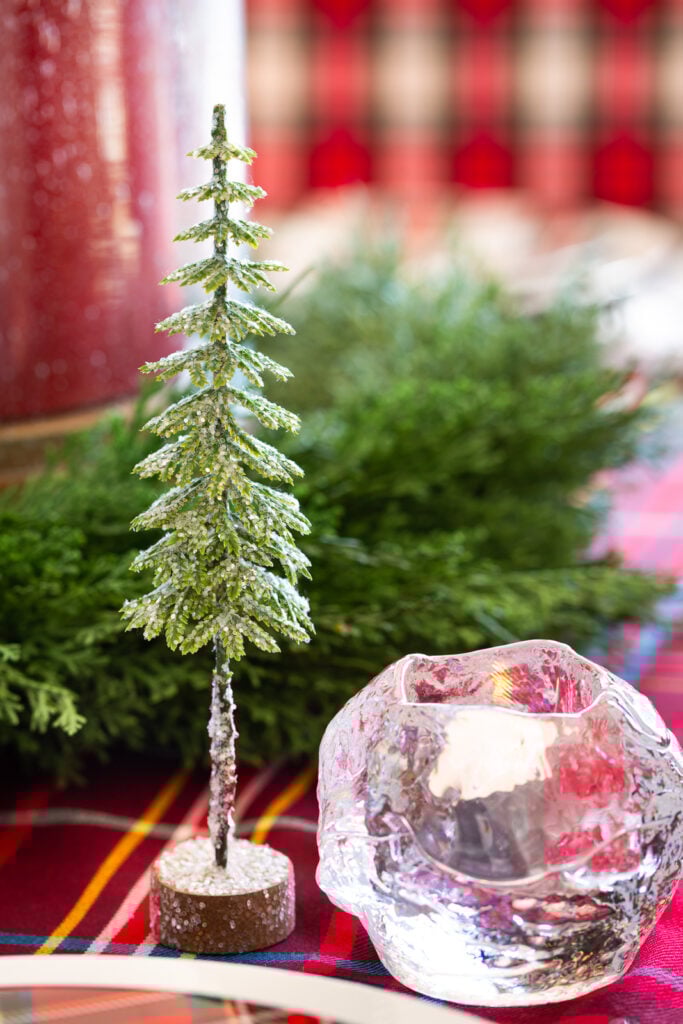 Cute glittered pine tree decoration from Hobby Lobby on table setting along with a Kosta Boda snowball votive holder.