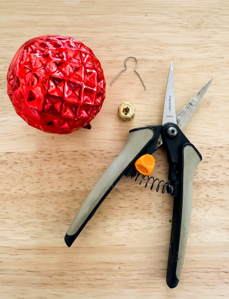 a red Christmas ornament with top taken out and cutting snips
