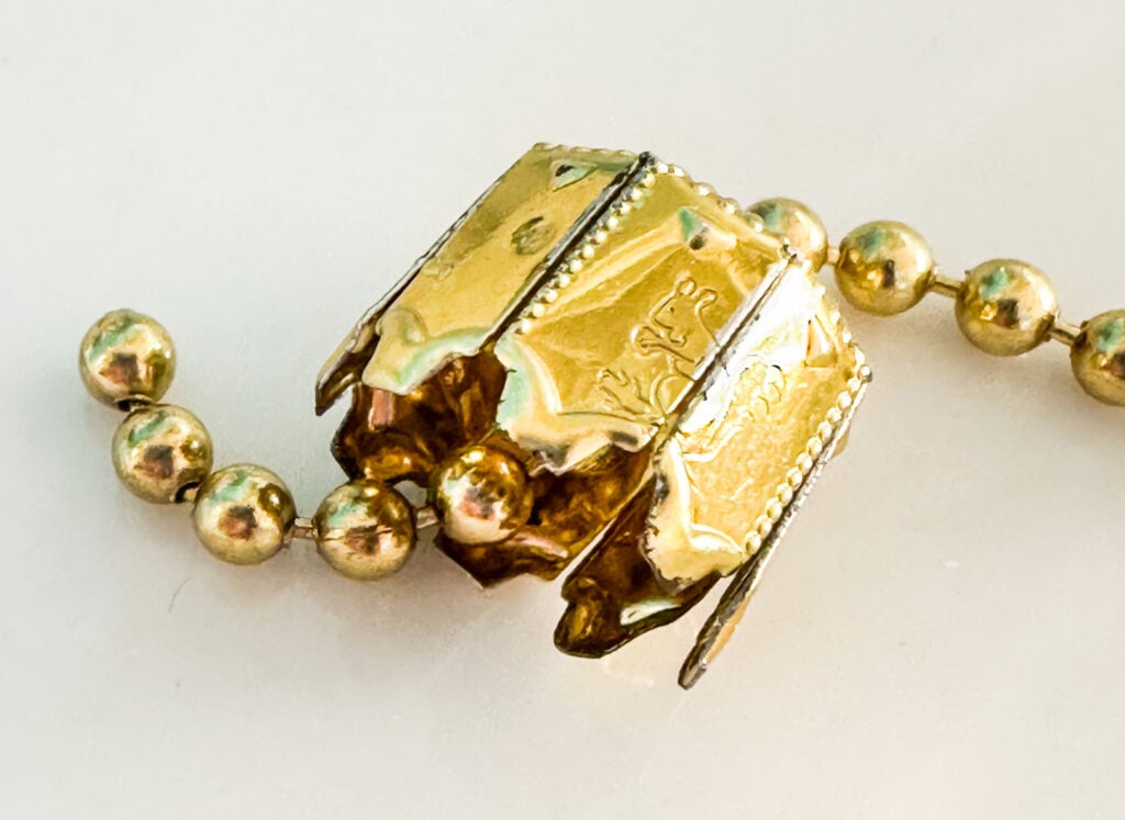 close up of how to thread ceiling fan chain through top of ornament top.