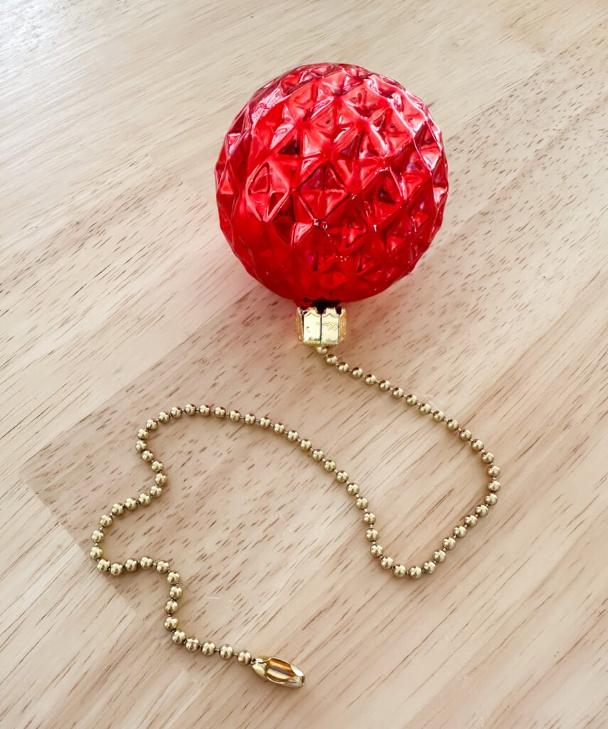 a close up of a Christmas ornament added to a ceiling fan pull chain to create festive holiday touch.