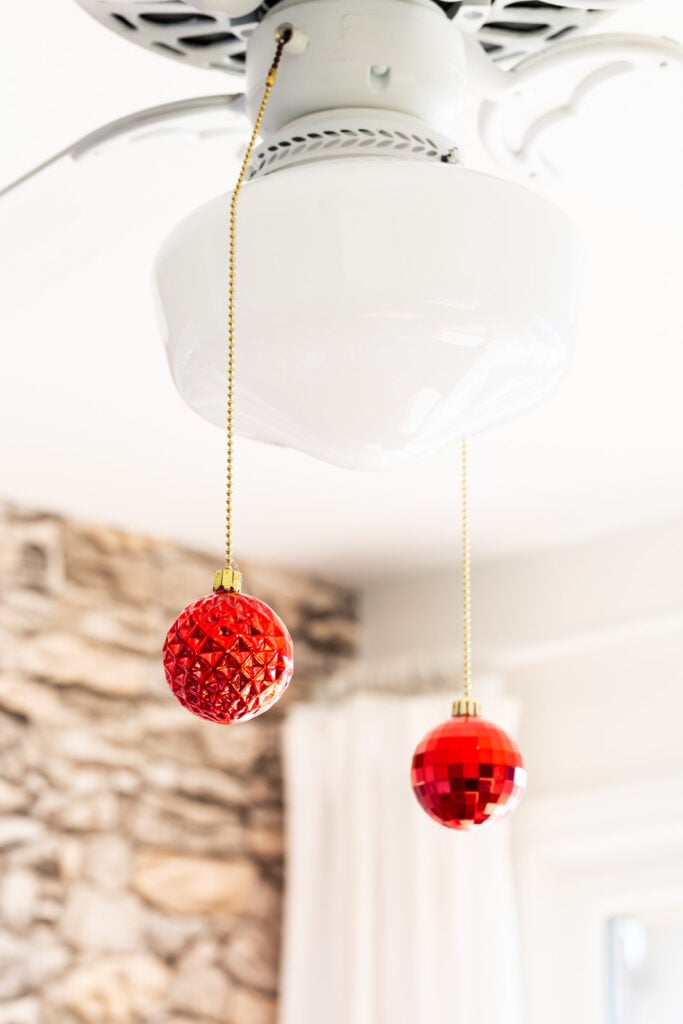two pull chains on a ceiling fan with Christmas ornaments added.