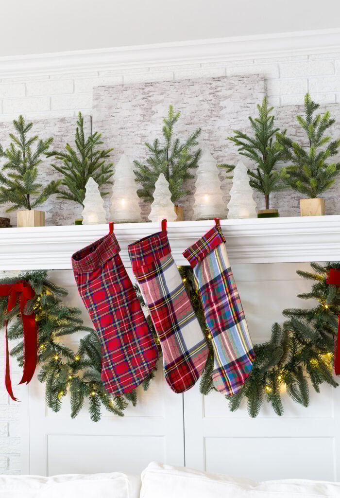 a fireplace mantel decorated for Christmas using green white and red plaid.