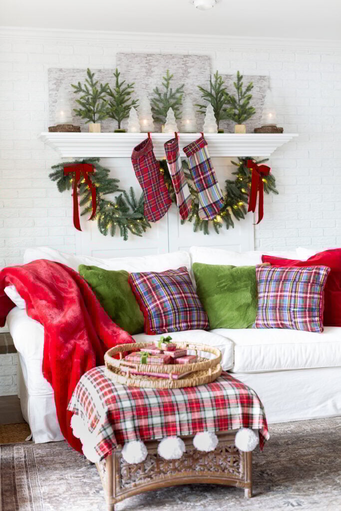 A living room with a classic red and green Christmas decorating color scheme with a modern touch of plaid and the texture of fur added.