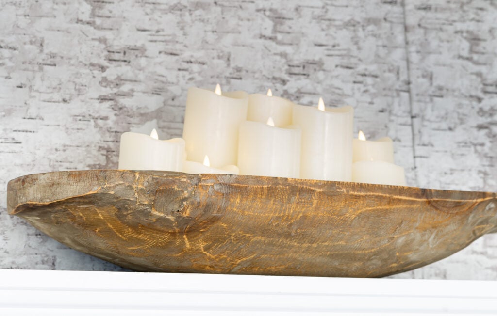 a grouping of battery operated candles in a wood dough bowl