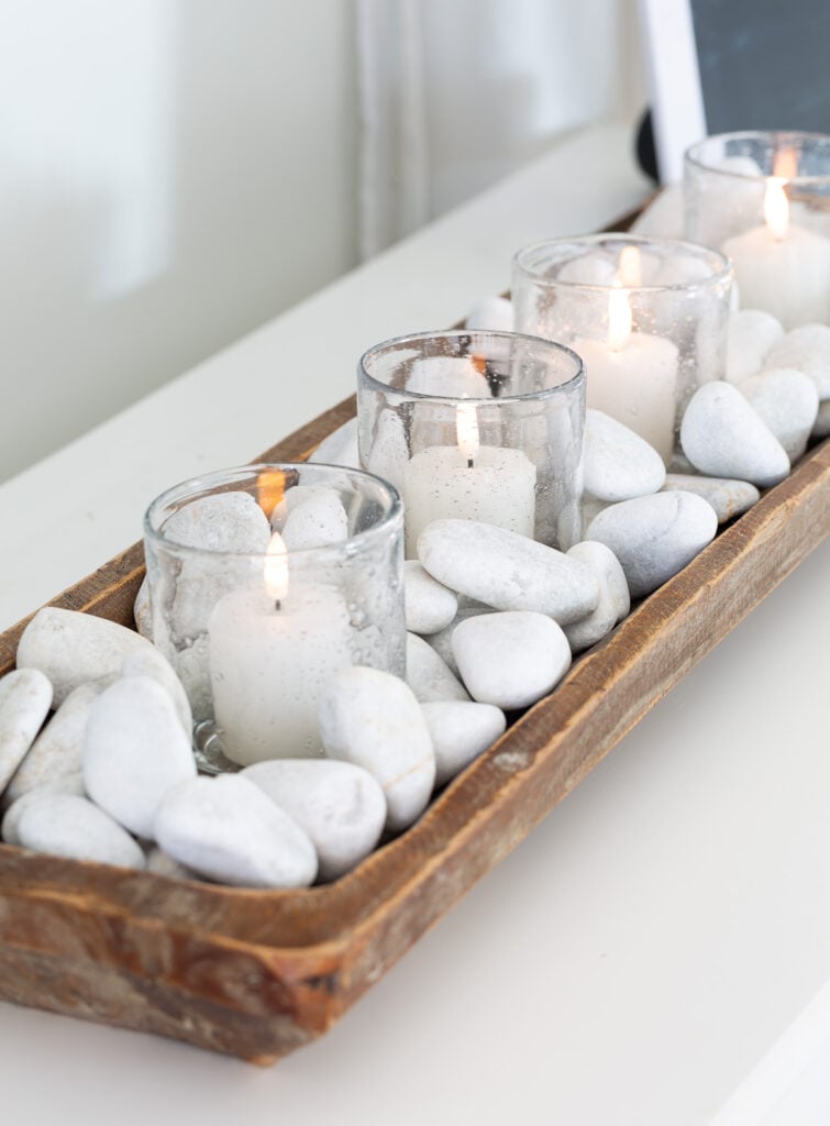 old-fashioned glasses with votive candles in a dough bowl filled with small white rocks.
