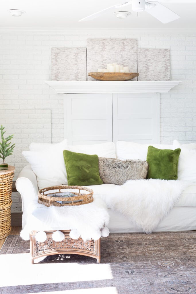 a fireplace wall in a living room that is decorated in a calm and peaceful neutral way with green accents