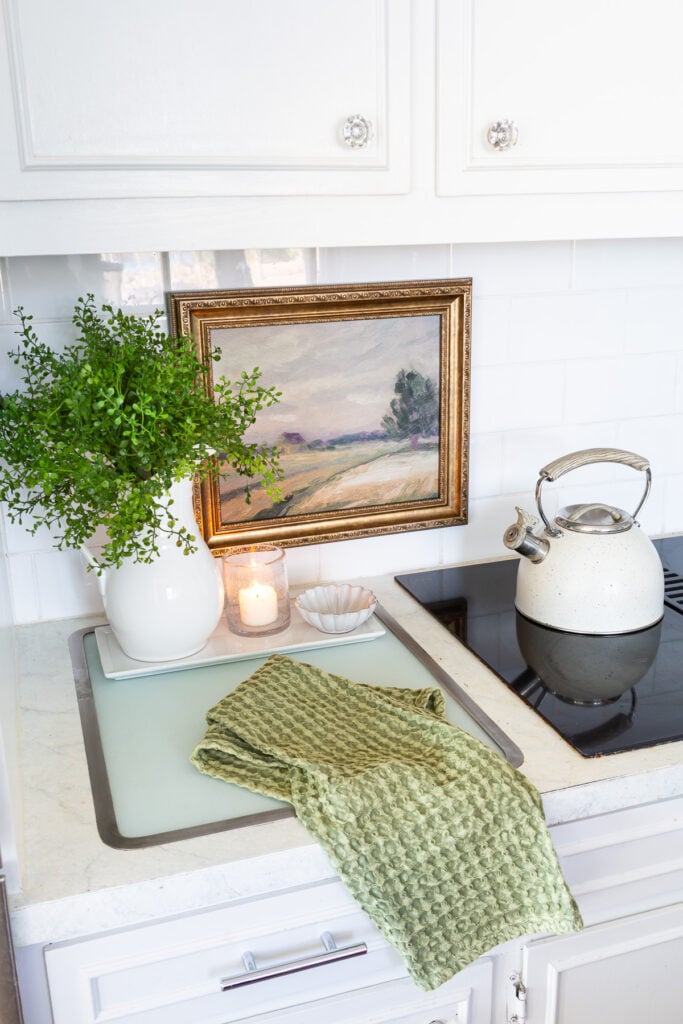 Looking down at a kitchen counter and white tile backsplash that has framed art hung on it.