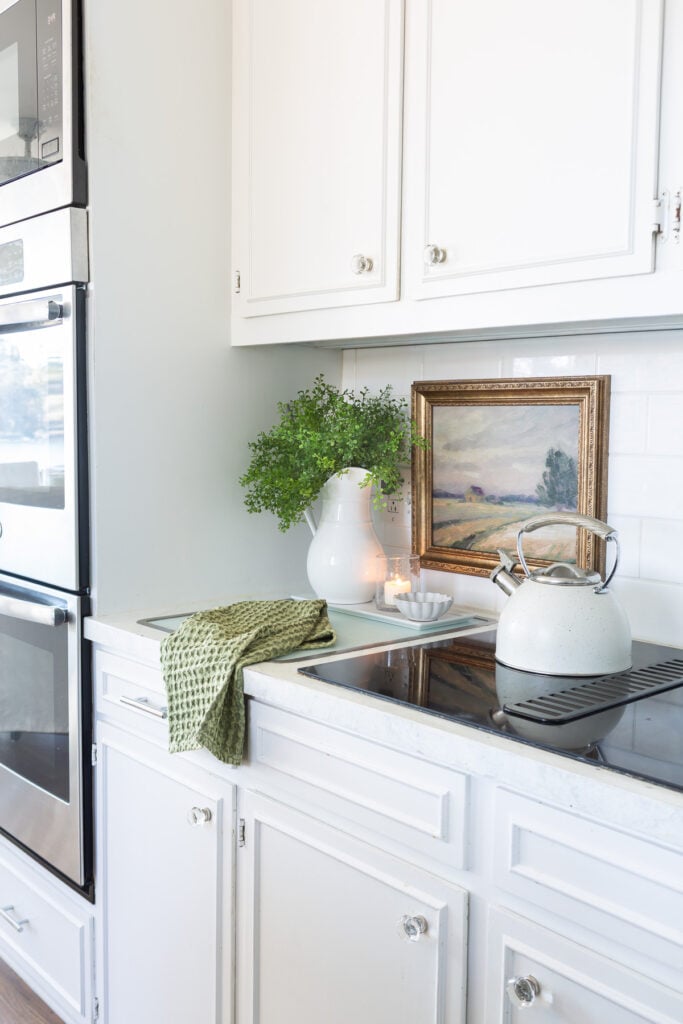 a view of a long wall in a kitchen where framed art is hung on the tile backsplash.