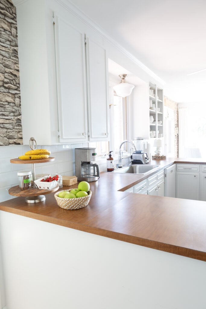 Looking a sink area in kitchen with white cabinets and brown Formica counters