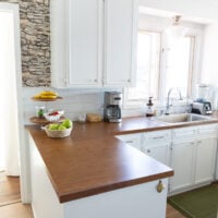 Looking a sink area in kitchen with white cabinets and brown Formica counters