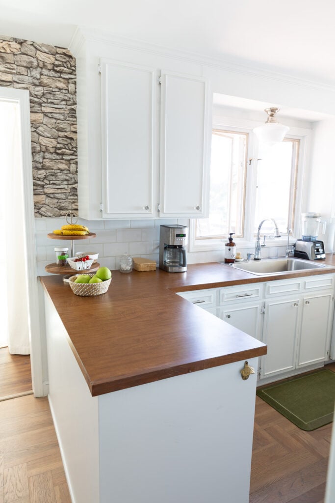 Looking a sink area in kitchen with white cabinets and brown Formica counters