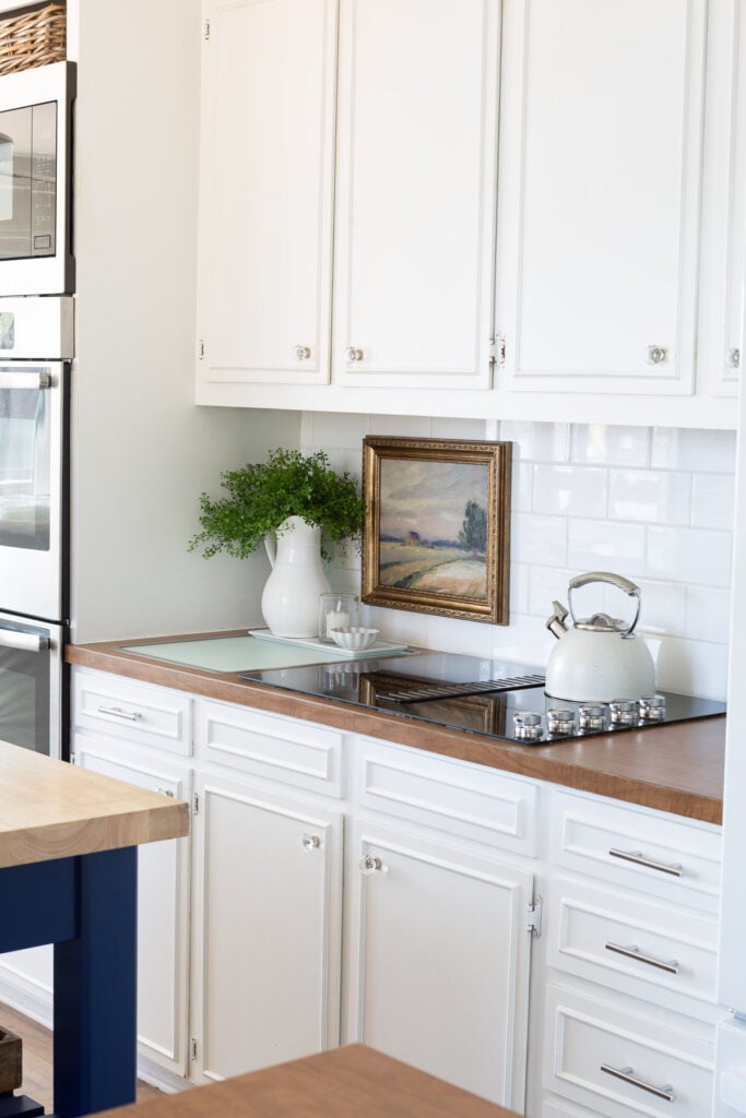 Looking a cooktop area in kitchen with white cabinets and brown Formica counters