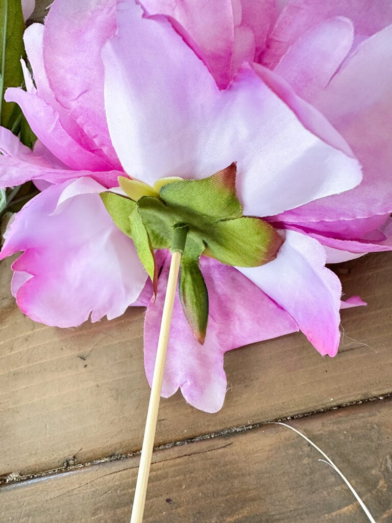 close up of how to place wood skewer into head of faux flower to be able to style the flowers in differnt ways in a home.