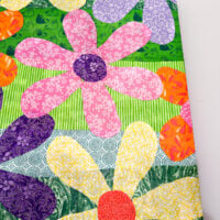 close up of colorful fabric flowers Mod Podged on a repurposed canvas