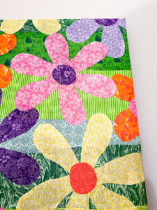 close up of colorful fabric flowers Mod Podged on a repurposed canvas