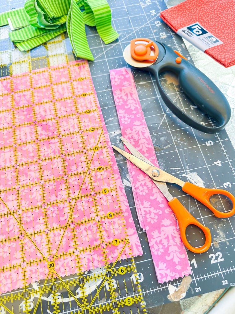 Cutting out strips of fabric with a rotary cutter and quilt ruler.