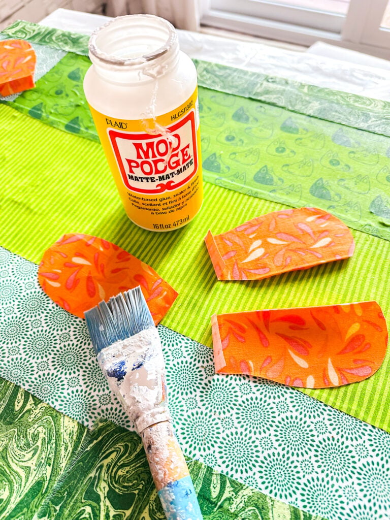Brushing Mod Podge on fabric flower petals to attach to canvas.
