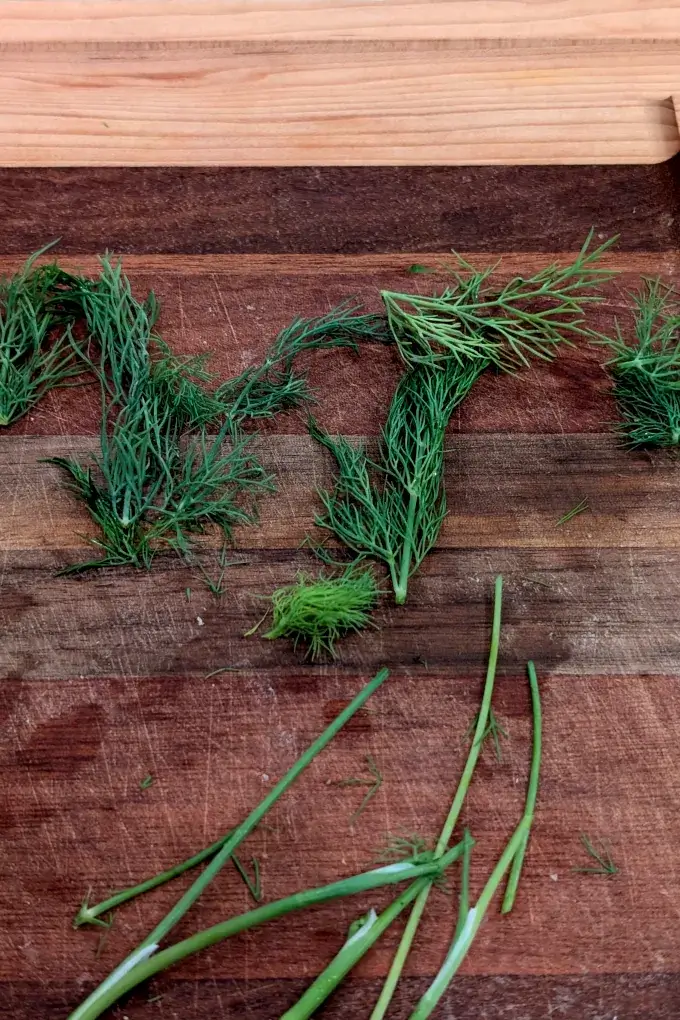 Dill weed on a cutting board with the fronds removed from the stems