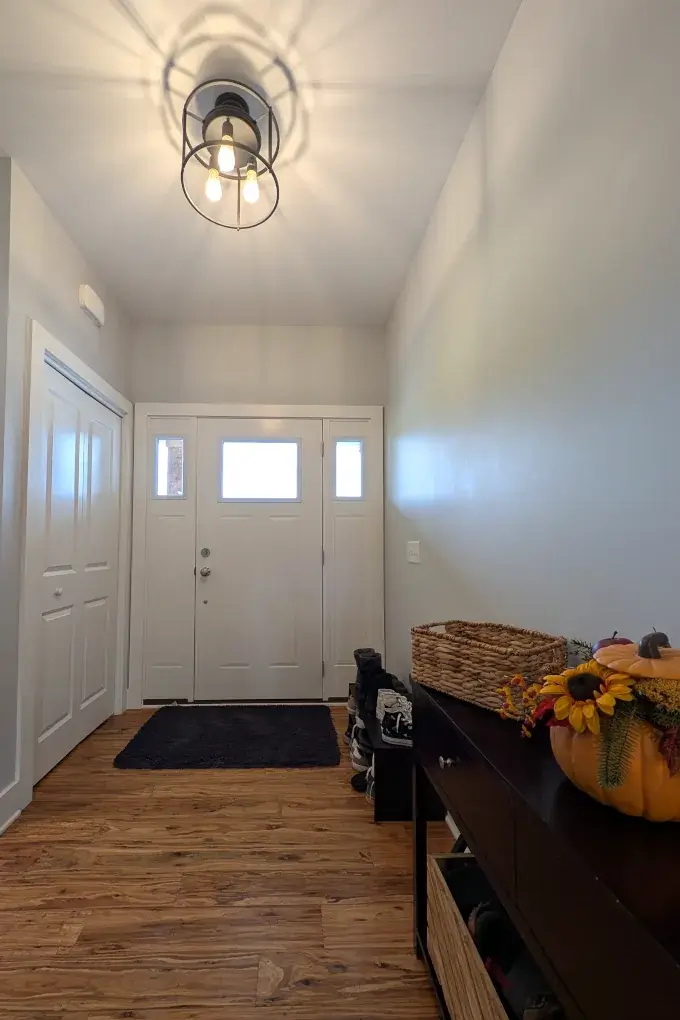 Front door from inside the house with bright entry light above and console table on the side