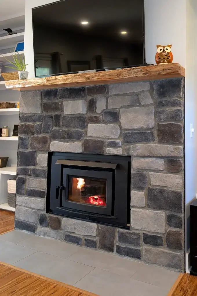Wood stove with stone surround and wood mantel