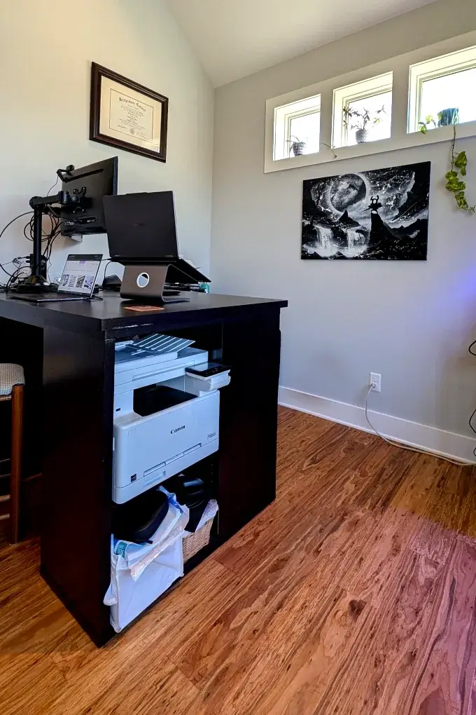 Home office with a large desk and windows on the wall