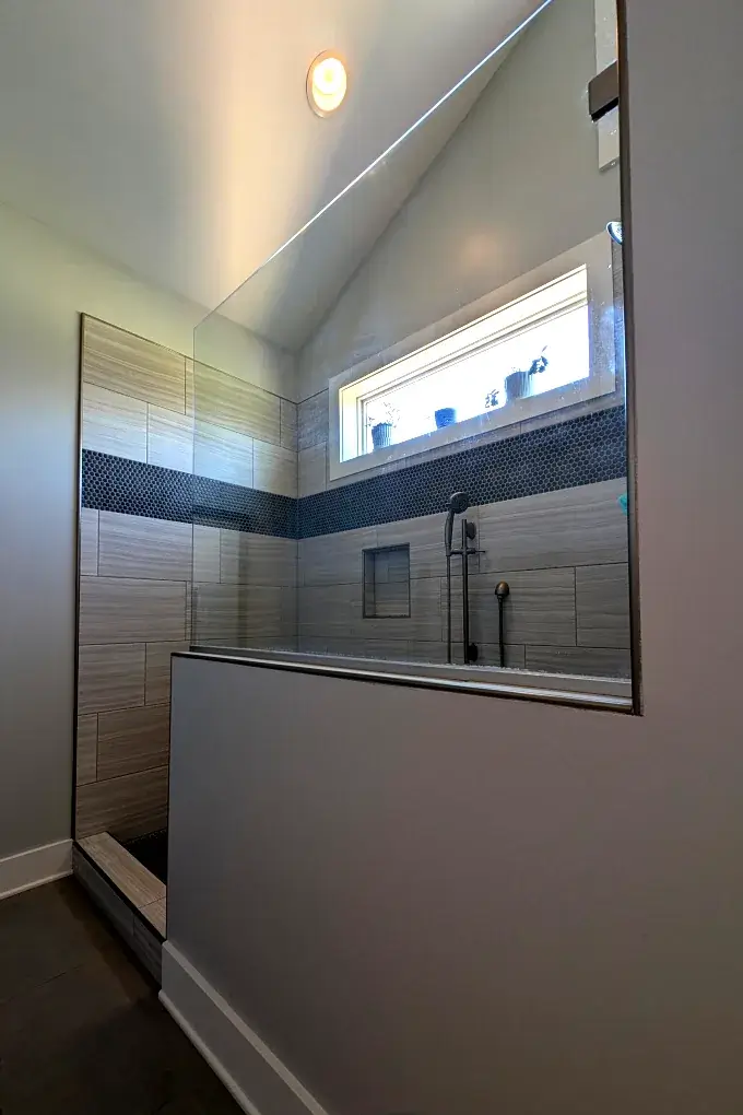 Shower with tiled walls and a penny tile accent